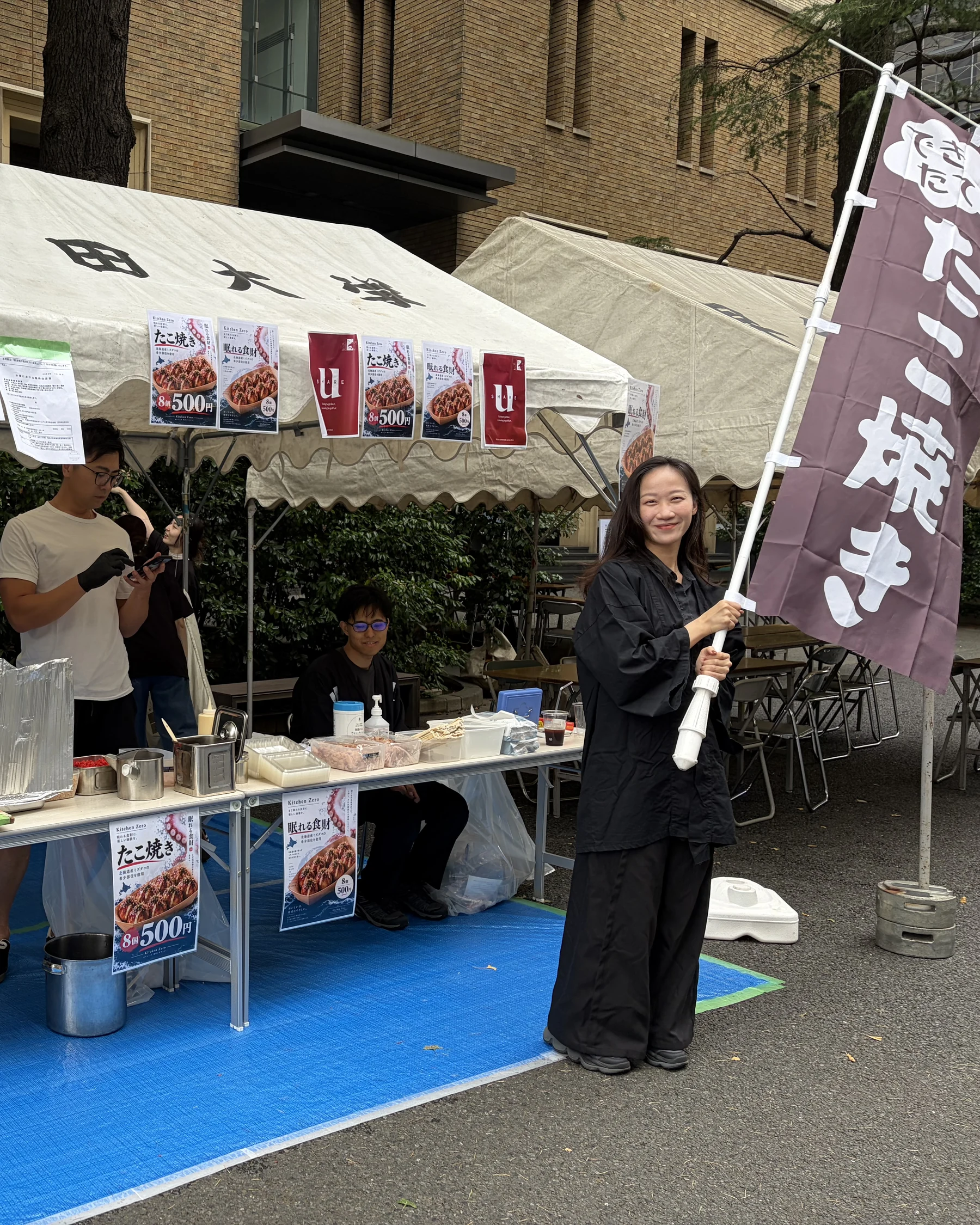 早稲田地球感謝祭のブースで、たこ焼きの幟を掲げるスタッフ